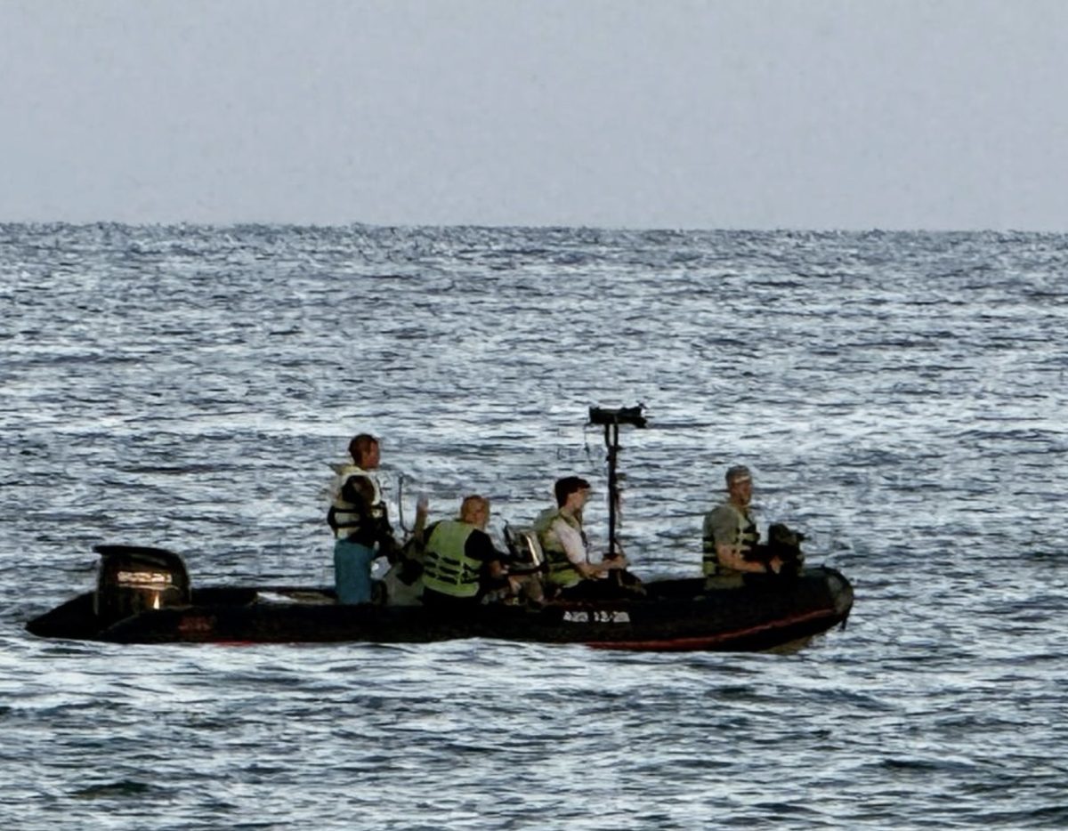 Lancha de rodaje en el mar con equipo de cámara y chalecos salvavidas