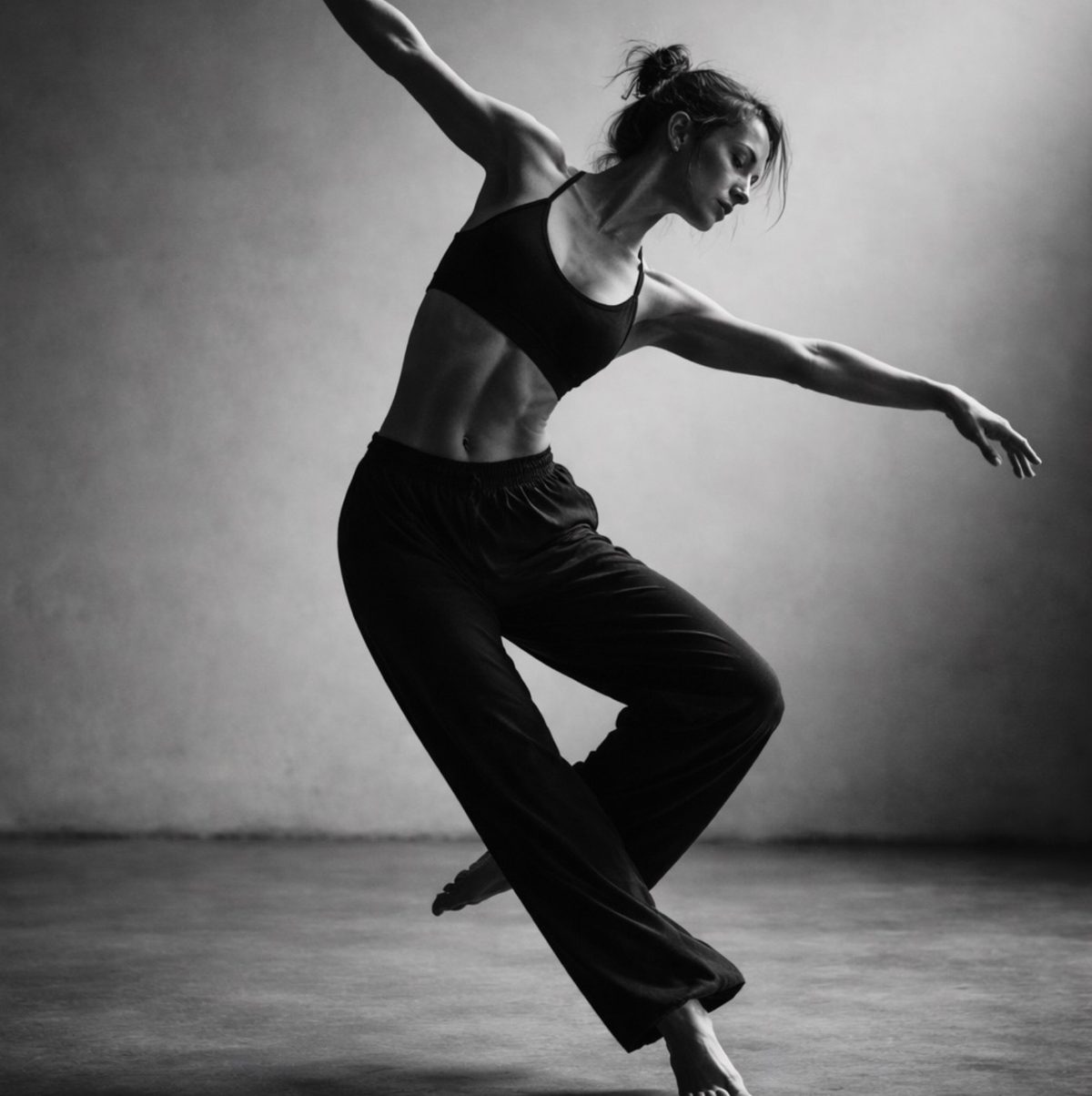 Bailarina en blanco y negro en pleno movimiento sobre un suelo de cemento