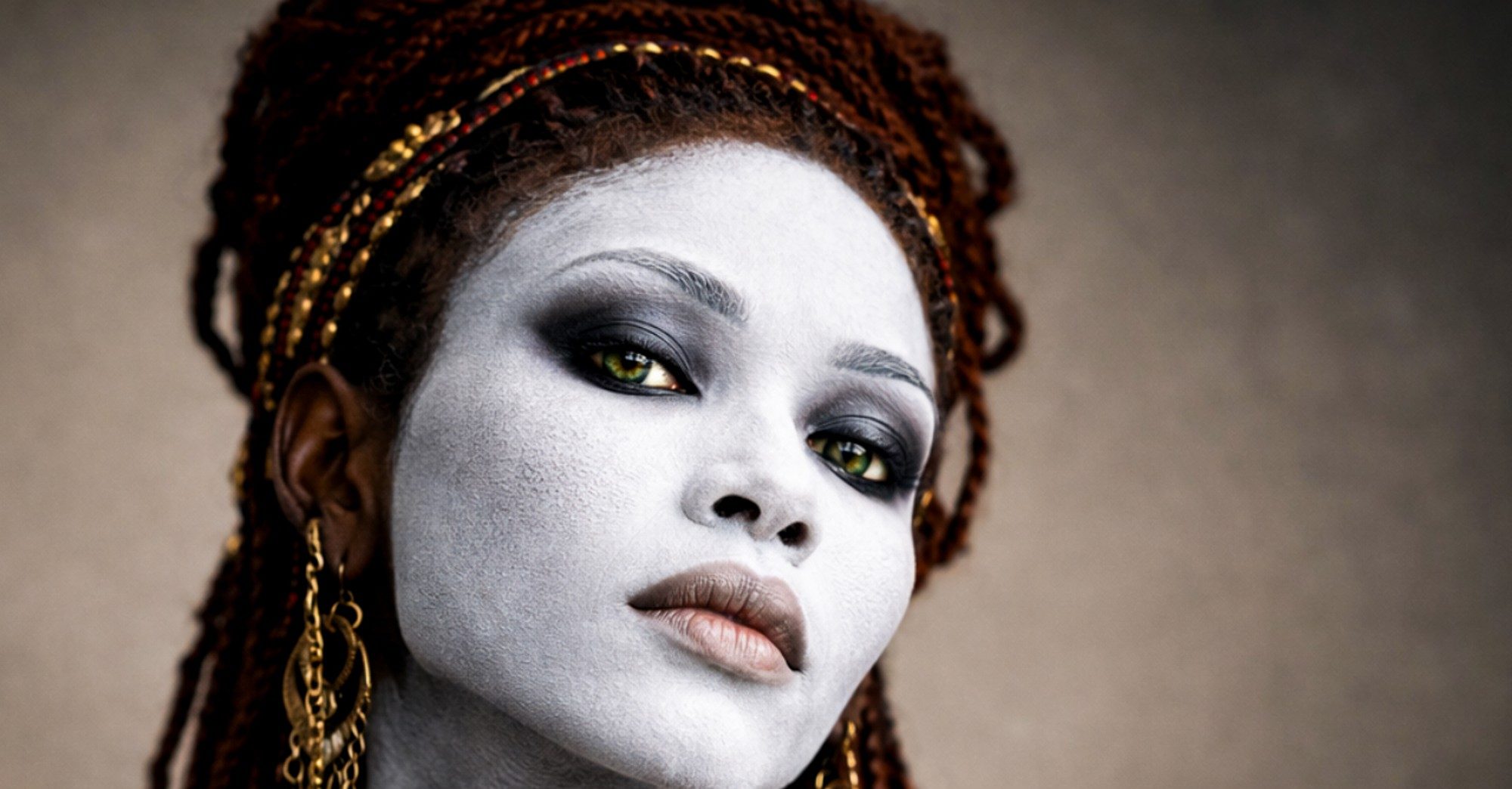 Retrato de una mujer negra con el rostro pintado de blanco, trenzas y joyas doradas